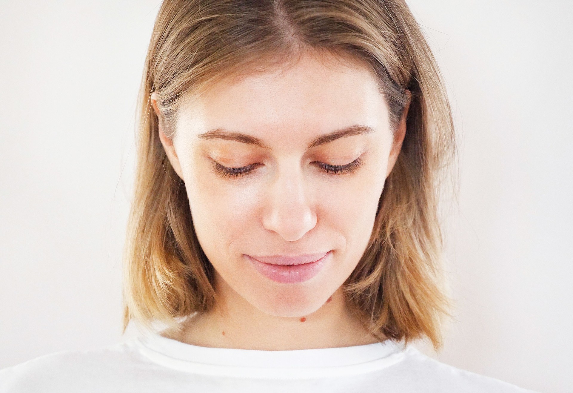 Portrait of young attractive blue-eyed blonde woman with short hair perfect smiling on light neutral background